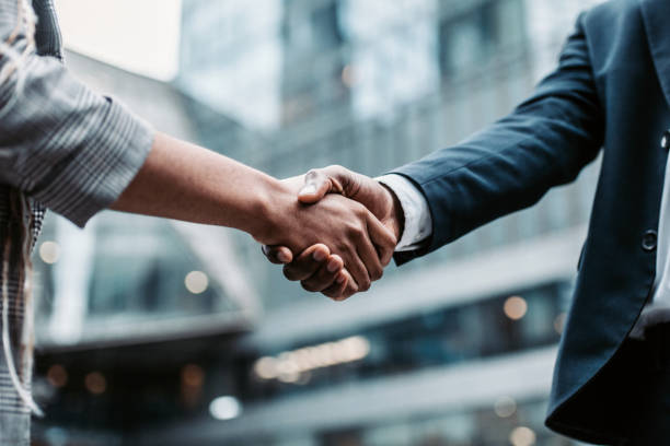 meeting success. two business persons shaking hands standing outside